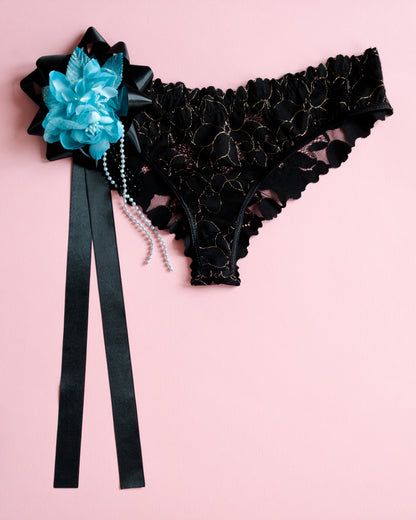 Black lace garter belt with blue flower and black ribbon on a pink background