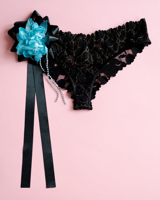 Black lace garter belt with blue flower and black ribbon on a pink background