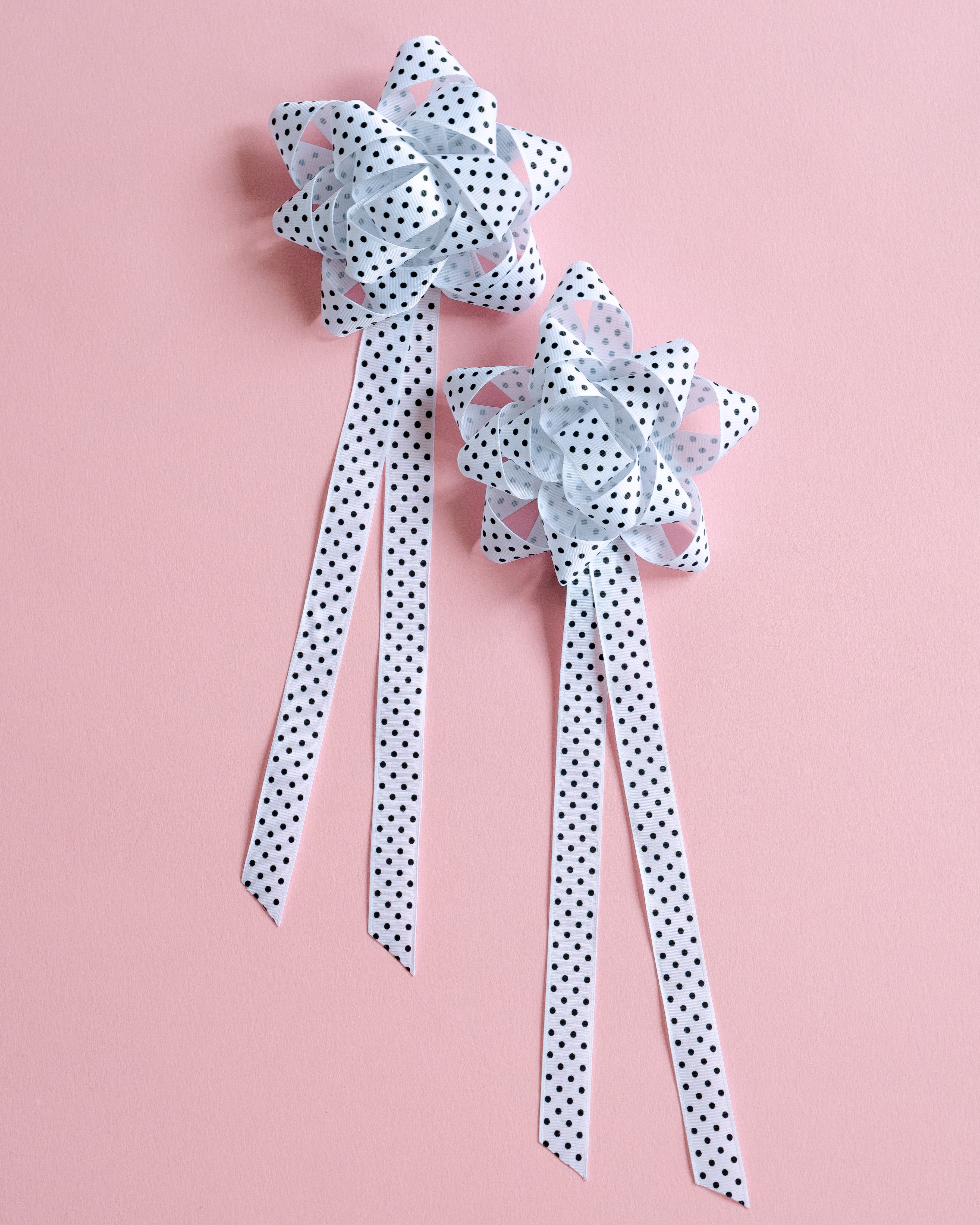 Two polka dot ribbons on a pink background
